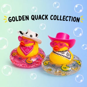May include: Two yellow rubber ducks in the Golden Quack Collection. The left duck wears a white cow-print cowboy hat, pink heart-shaped sunglasses, and a pink bandana. The right duck wears a pink cowboy hat, pink heart-shaped sunglasses, and a black and white bandana. Both sit in clear inflatable swim rings.