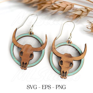 May include: A pair of wooden earrings with a turquoise blue circle and a cutout of a bull skull. The earrings are on a white background.