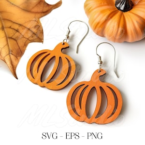 Könnte beinhalten: Orangefarbene Holzohrringe in Kürbisform mit silbernen Haken. Die Ohrringe haben ein geschnitztes Design. Ein getrocknetes Blatt und ein kleiner Kürbis sind im Hintergrund. Der Text "SVG - EPS - PNG" steht unten.