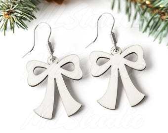 May include: A pair of white wooden bow earrings with silver hooks. The earrings are shaped like a bow with a loop at the top.