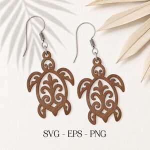 May include: A pair of brown wooden earrings featuring a laser-cut sea turtle design with intricate filigree patterns inside the shell. The earrings hang from silver-toned metal hooks. The text SVG - EPS - PNG is printed at the bottom.