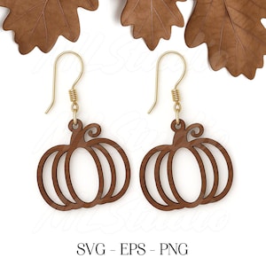 May include: A pair of wooden pumpkin earrings with gold-colored ear wires. The earrings are a dark brown color and have a cutout design. The image also includes the text "SVG - EPS - PNG".