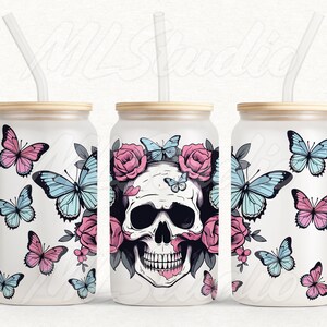 May include: Three white tumblers with a skull and floral design. Each tumbler has a straw and a wooden lid. The skull is surrounded by pink roses and butterflies. The butterflies are pink and blue.