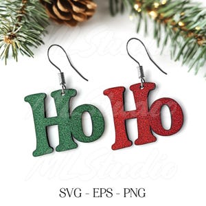 May include: A pair of dangle earrings with the word "Ho Ho" written on them. One earring is green and the other is red.