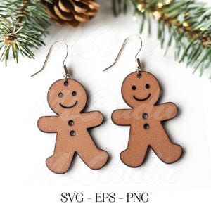 May include: A pair of wooden gingerbread man earrings with a smiling face and two buttons. The earrings are brown and have a silver hook.