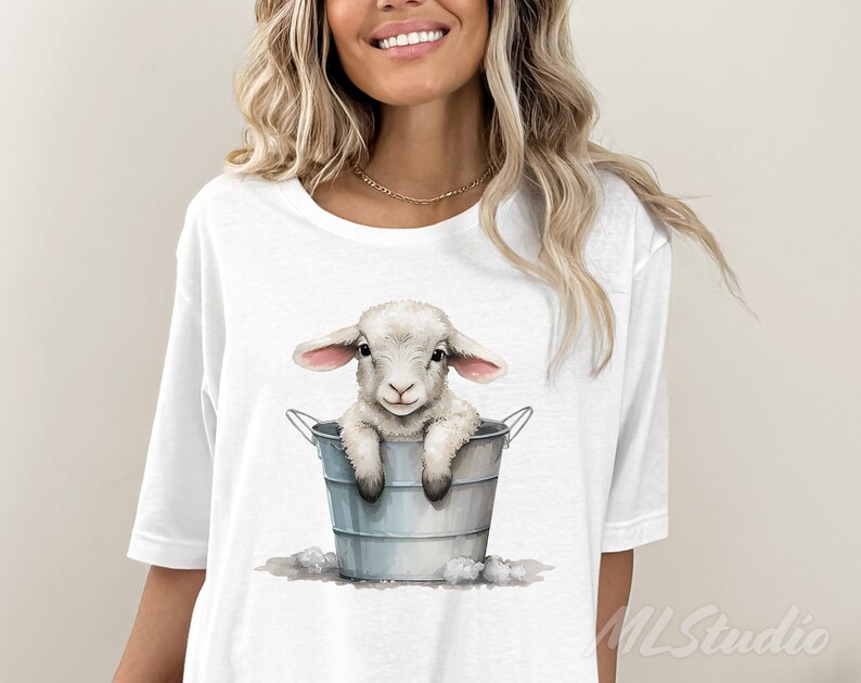 Puede incluir: Camiseta blanca con un gr&aacute;fico de un cordero blanco sentado en un cubo de metal gris. El cordero tiene orejas rosas y una expresi&oacute;n dulce.