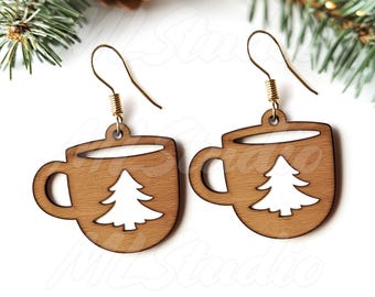 Op de afbeelding: Een paar houten oorbellen in de vorm van koffiemokken met een kerstboomuitsparing. De oorbellen zijn bruin met een witte boomuitsparing.