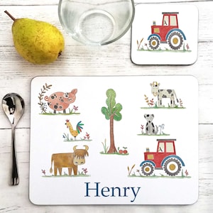 May include: A white personalized placemat with a farm theme. The placemat features a pig, a cow, a dog, a rooster, a tree, a tractor, and a highland cow. The placemat is personalized with the name "Henry".