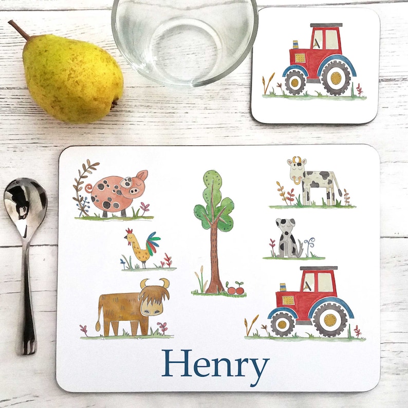 May include: A white personalized placemat with a farm theme. The placemat features a pig, a cow, a dog, a rooster, a tree, a tractor, and a highland cow. The placemat is personalized with the name "Henry".