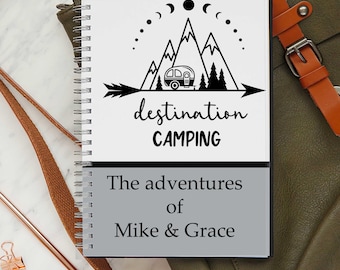 May include: A spiral-bound notebook with a camping theme. The top section features a black graphic of mountains, a camper, and the words "destination CAMPING." The bottom section reads "The adventures of Mike & Grace."