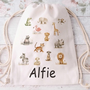 May include: A cream-coloured drawstring bag decorated with watercolour illustrations of safari animals such as a zebra, lion, and giraffe. The name "Alfie" is printed in black script. The bag has a cream-coloured rope drawstring.