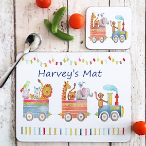 Peut inclure: Un set de table blanc avec un motif de train coloré mettant en scène des animaux comme un lion, une girafe, un éléphant et un singe. Le set de table porte l'inscription "Harvey's Mat".