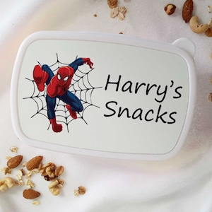 May include: White lunchbox featuring a Spiderman graphic and the text "Harry's Snacks".