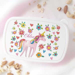 May include: White lunchbox featuring a pink unicorn and rainbow design. The unicorn is surrounded by colourful flowers and hearts. The lunchbox is personalised with the name "Chloe".