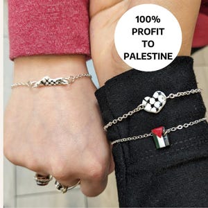 May include: Two silver bracelets with charms. One bracelet has a charm of a Palestinian flag, the other has a charm of a heart with a checkered pattern. The bracelets are on the wrists of two people. The text "100% PROFIT TO PALESTINE" is in a circle above the bracelets.