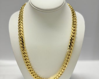 May include: A gold curb chain necklace on a white display stand.