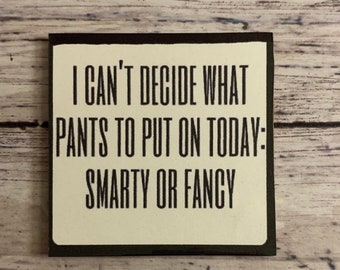 May include: A white sign with black text that reads "I can't decide what pants to put on today: Smarty or Fancy". The sign has a black frame.