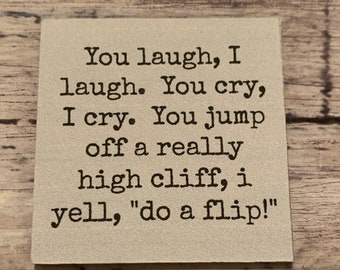May include: A beige square sign with black text that reads "You laugh, I laugh. You cry, I cry. You jump off a really high cliff, i yell, "do a flip!"