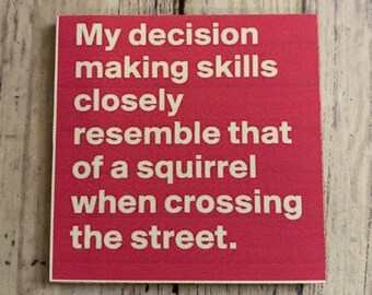 May include: A red wooden sign with white text that reads "My decision making skills closely resemble that of a squirrel when crossing the street."