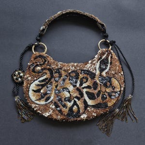 Pode incluir: Uma caneca de cerâmica branca com uma alça preta e o texto "But First, Coffee" em negrito preto. A caneca está em um fundo desfocado. A caneca tem aproximadamente 10 cm de altura.