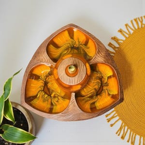 May include: A vintage serving tray with a triangular shape and three sections. The tray has a wood-grain texture on the outer rim and a central circular section. The interior sections are filled with a vibrant orange and gold resin. A small gold accent is in the center.