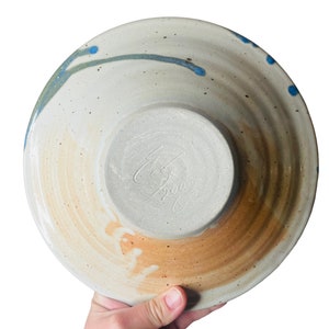 K&ouml;nnte beinhalten: Eine wei&szlig;e Keramiksch&uuml;ssel mit blauem und gr&uuml;nem Glase. Die Sch&uuml;ssel hat einen braunen Rand und eine Signatur auf der Unterseite, die "C.B. 2003" lautet.