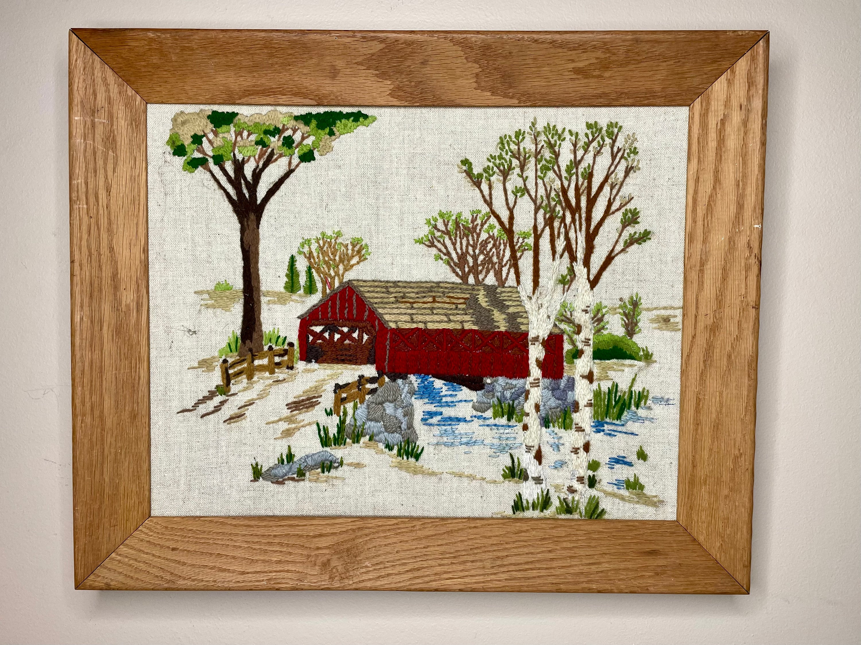Rustic Handmade Vintage Crewel Embroidery Wall Hanging of a Covered Bridge, in a Small Town with Natural Trees/Florals in a Wood Frame 17x14
