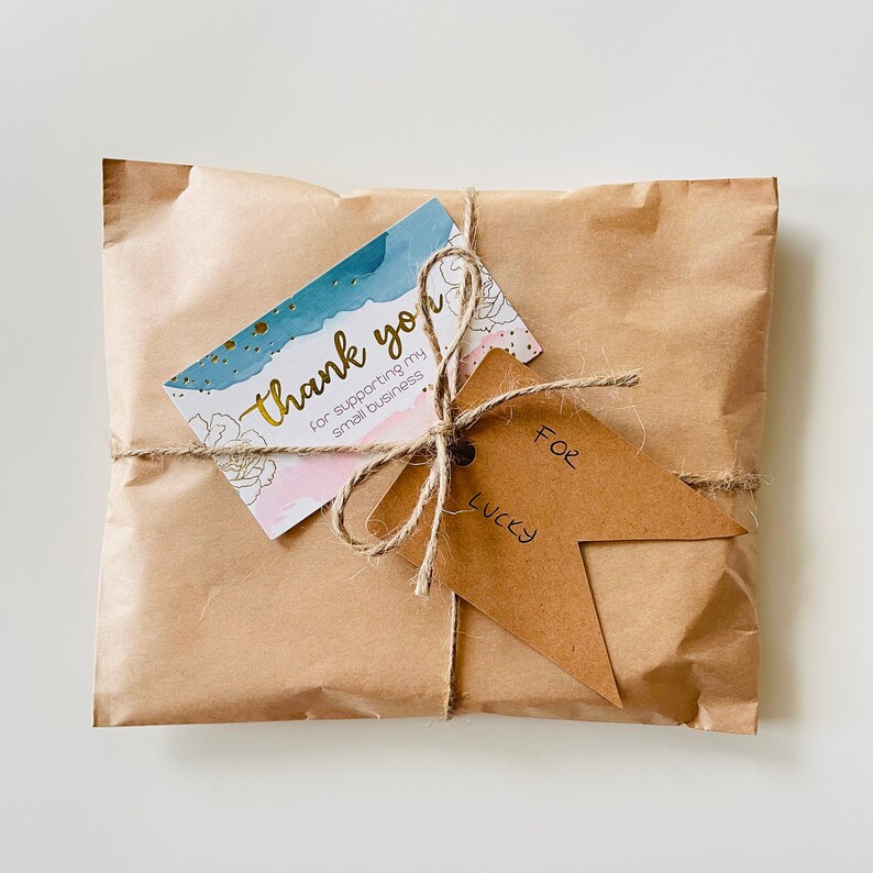 Puede incluir: Un paquete de papel marr&oacute;n atado con cuerda y una tarjeta de agradecimiento que dice "Gracias por apoyar mi peque&ntilde;o negocio". Una etiqueta m&aacute;s peque&ntilde;a est&aacute; unida a la cuerda y dice "Para Lucky".