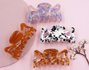 May include: Four different hair clips in various colours and patterns. The clips are made of plastic and have a claw-like design. The clips are a popular hair accessory for women.