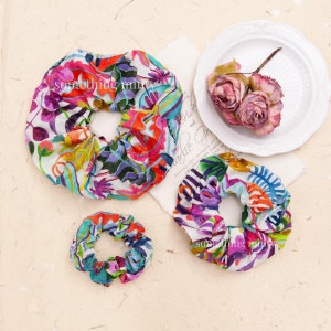 May include: Three colorful fabric scrunchies with the text "something mint" printed on them. The scrunchies are in various floral patterns with pink, blue, green, and yellow colors.