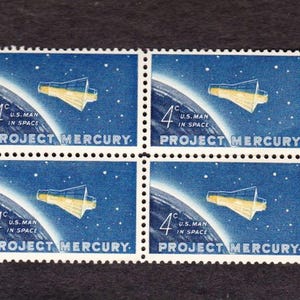 May include: Four vintage postage stamps featuring a spacecraft in space, with a blue and white background. The stamps read "4¢ U.S. MAN IN SPACE PROJECT MERCURY."