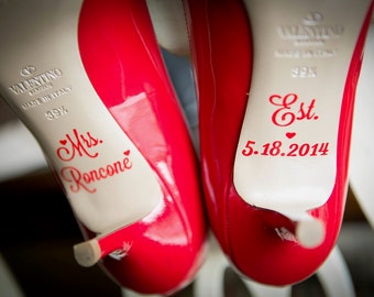 May include: Pair of red Valentino high heels with white soles. The soles are inscribed with "Mrs. Roncone" and "Est. 5.18.2014" in red script. The shoes are size 39 and made in Italy.