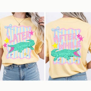 Peut inclure: T-shirt jaune clair avec un motif d'alligator vert. Le devant du t-shirt porte l'inscription "LATER" et le dos "AFTER WHILE". Le motif comprend des étoiles roses, des nœuds bleus et des étoiles jaunes. Vêtement décontracté.