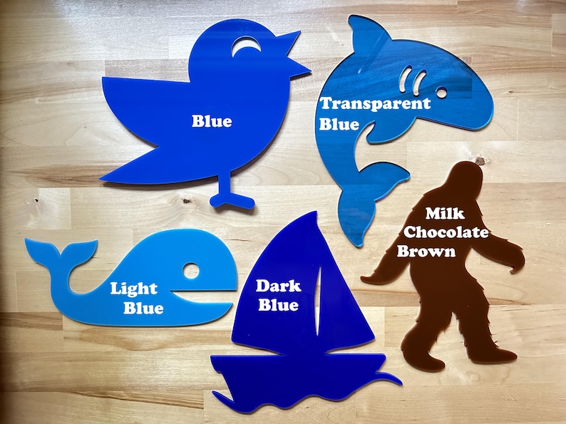 May include: A collection of acrylic cutouts in various shapes and colors. Includes a blue bird, a shark with transparent blue, a whale in light blue, a sailboat in dark blue, and a brown Bigfoot. Each cutout has a color label.