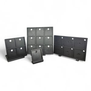 May include: A collection of black, modular display units. Each unit features square compartments with a circular opening and a small stand. The units are arranged in various configurations, showcasing their versatility for product display.