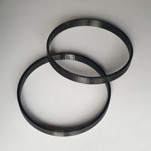 Pode incluir: Dois anéis de plástico preto, um ligeiramente maior que o outro, estão empilhados um em cima do outro.