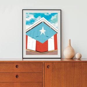 May include: A framed print of a building with a red, white, and blue design that resembles the Puerto Rican flag. The building is angled and the sky is visible in the background.