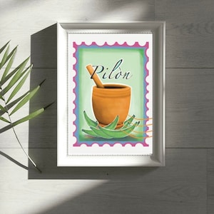 May include: A framed print with a green background featuring a brown mortar and pestle with the word "Pilon" in a decorative font. The print is surrounded by a blue, purple, and pink border.