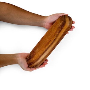 Peut inclure: Un plateau de service en bois long et ovale avec une finition en bois naturel. Le plateau est fait de bois brun clair avec des stries brun foncé.