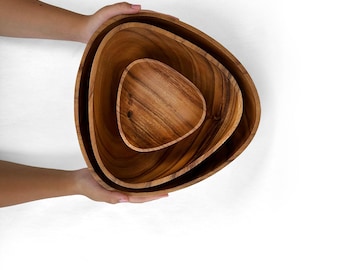 May include: Set of three wooden bowls in a triangular shape. The bowls are nested inside each other, with the largest bowl at the bottom and the smallest bowl at the top.