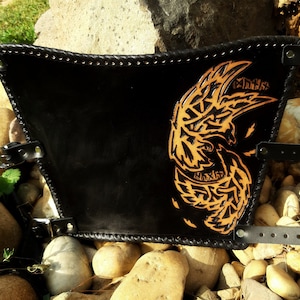 May include: Black leather arm guard with a detailed orange leather design of a bird with intricate patterns. The arm guard has adjustable straps with metal buckles.