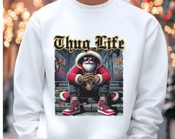 May include: White sweatshirt featuring a graphic of Santa Claus in a red coat, sunglasses, and gold jewelry, with the words "Thug Life" above. Santa is sitting on steps, wearing red and white sneakers.