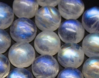 Puede incluir: Una colección de 18 cabujones de piedra lunar iridiscente, cada uno con una variación de color azul y blanco única. Las piedras son lisas y pulidas, con una forma redondeada.