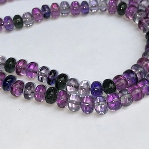 May include: A strand of purple, pink, and green glass beads. The beads are round and have a smooth, polished finish.