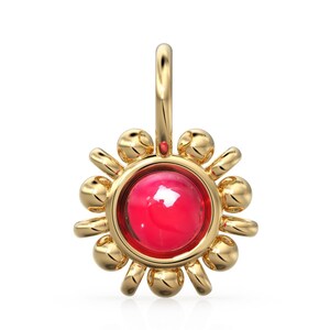 May include: A gold charm with a red gemstone in the center surrounded by a circle of smaller gold beads. The charm is shaped like a sun.