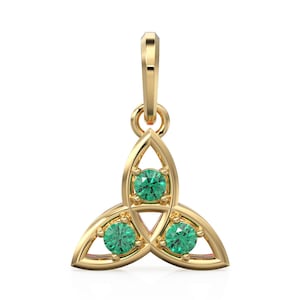 Może przedstawiać: Złoty wisiorek w kształcie celtyckiego węzła, z trzema zielonymi kamieniami szlachetnymi. Wisiorek ma pętlę na górze na łańcuszek. Kamienie szlachetne są okrągłe i osadzone w skomplikowanym wzorze węzła. Wisiorek jest prawdopodobnie wykonany ze złota.