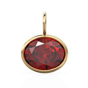 May include: A gold pendant featuring a large, faceted, oval-shaped, deep red gemstone. The gemstone is set in a gold bezel and has a small gold loop at the top for a chain. The pendant is displayed against a white background.