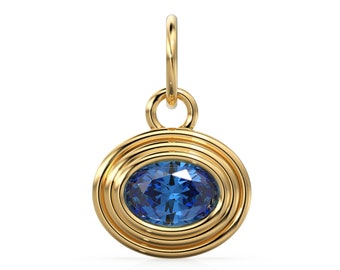 May include: A gold pendant with a blue oval gemstone set in a circular frame. The pendant has a loop at the top for attaching to a chain.