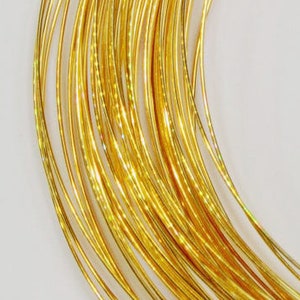 May include: A spool of gold-colored wire, wound tightly in a coil.
