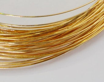 May include: A close-up of a coil of thin, shiny, gold-colored wire. The wire is tightly wound, creating a circular pattern. The bright gold color suggests a precious metal, possibly used for jewelry making or other crafts.